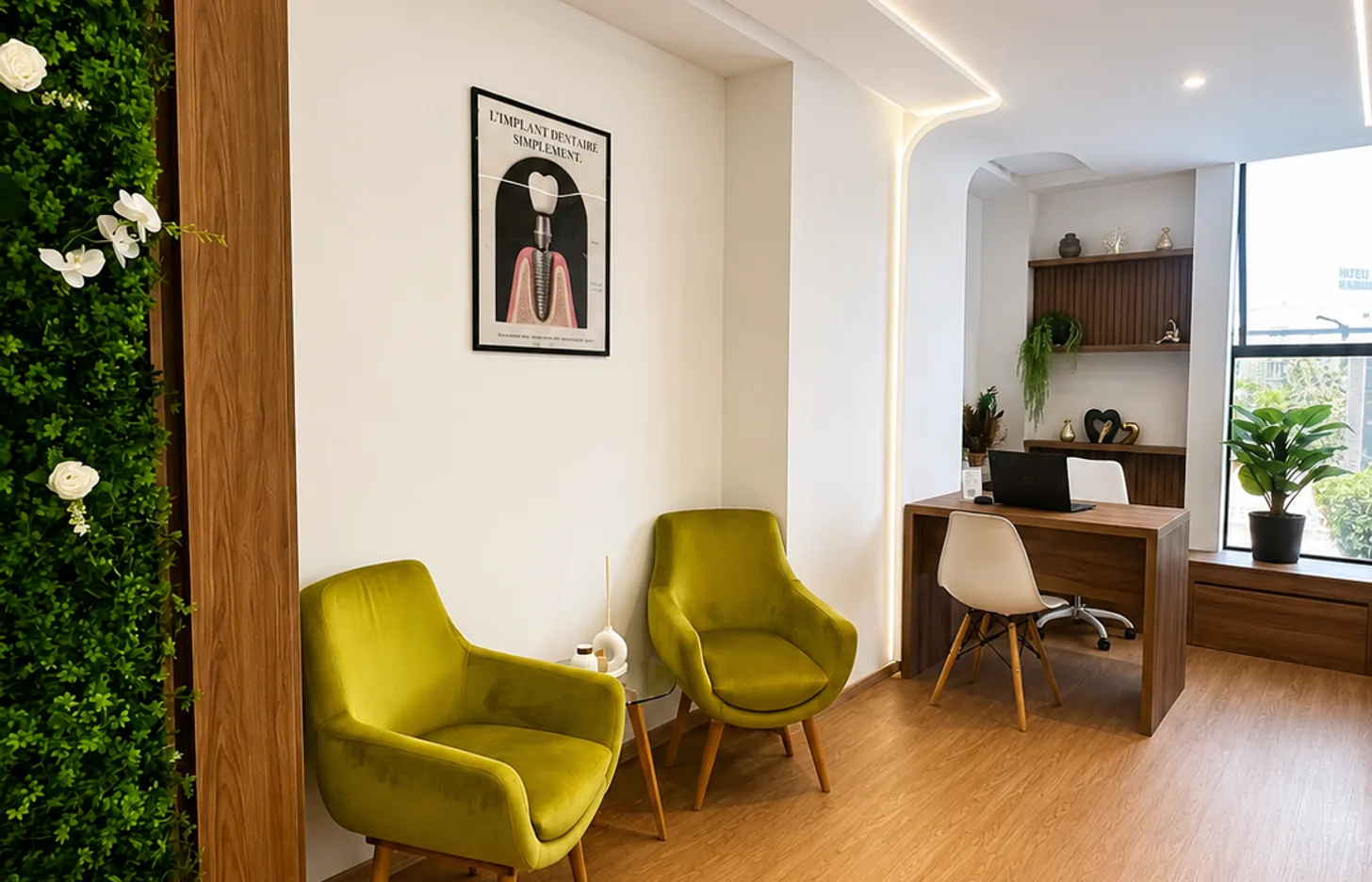 Salon d’attente du cabinet dentaire avec fauteuils verts et mur végétal à Kénitra
